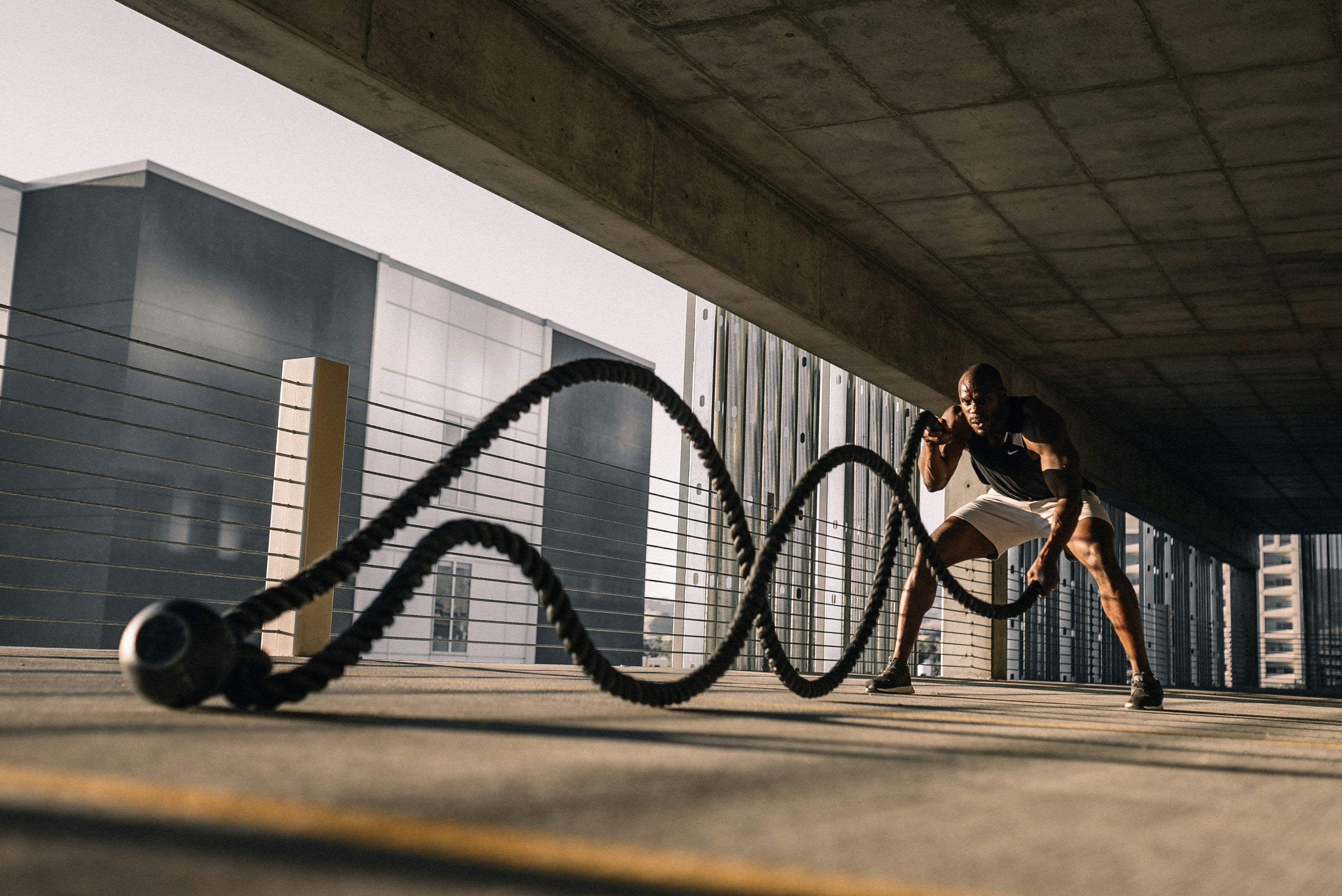 An athlete training with battle ropes outdoors, highlighting hydration, sweat loss and performance during intense exercise.