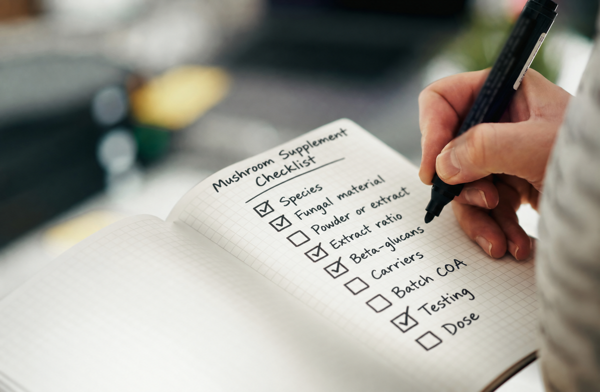Hand writing a mushroom supplement checklist in a notebook