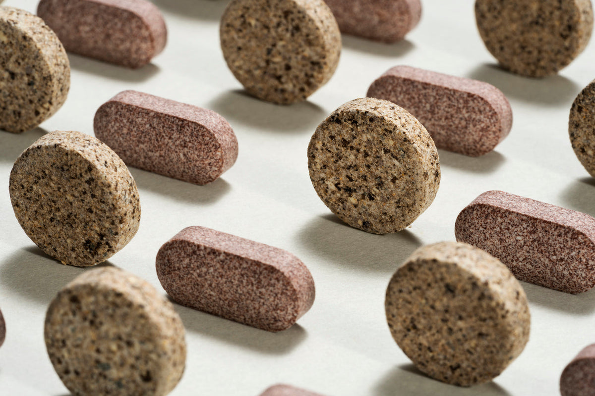 Assorted round and oval supplement tablets arranged on a light surface.