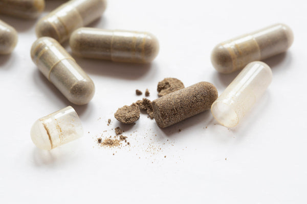 Opened supplement capsules with powder spilling out, representing filler and cutting agents in supplements.