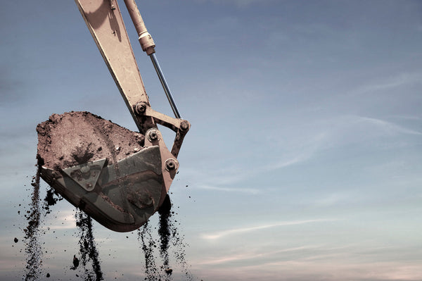 Excavator lifting and dumping soil, symbolising excessive loading.