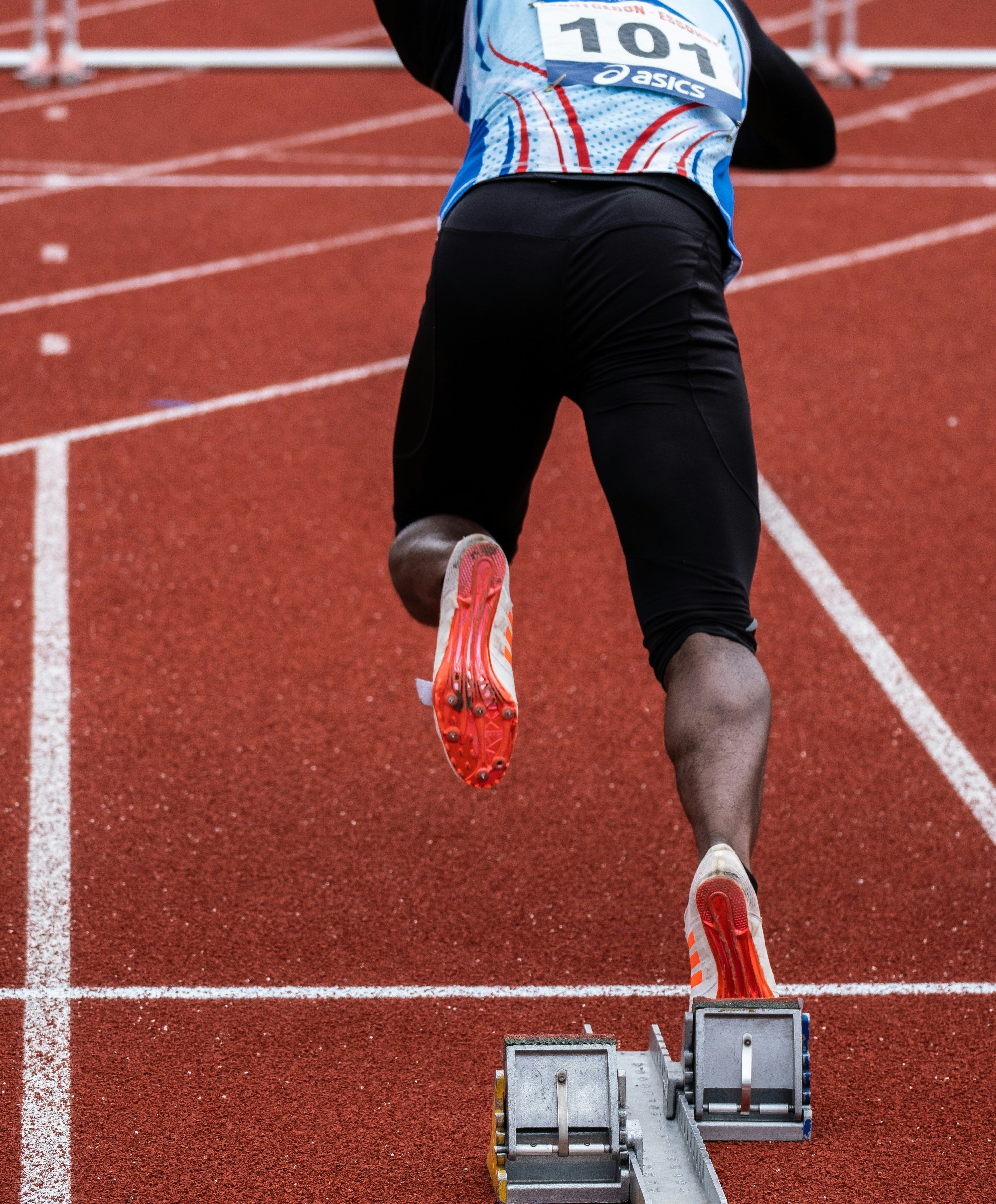 Athlete running on a track, representing sodium, hydration and electrolyte support during training.