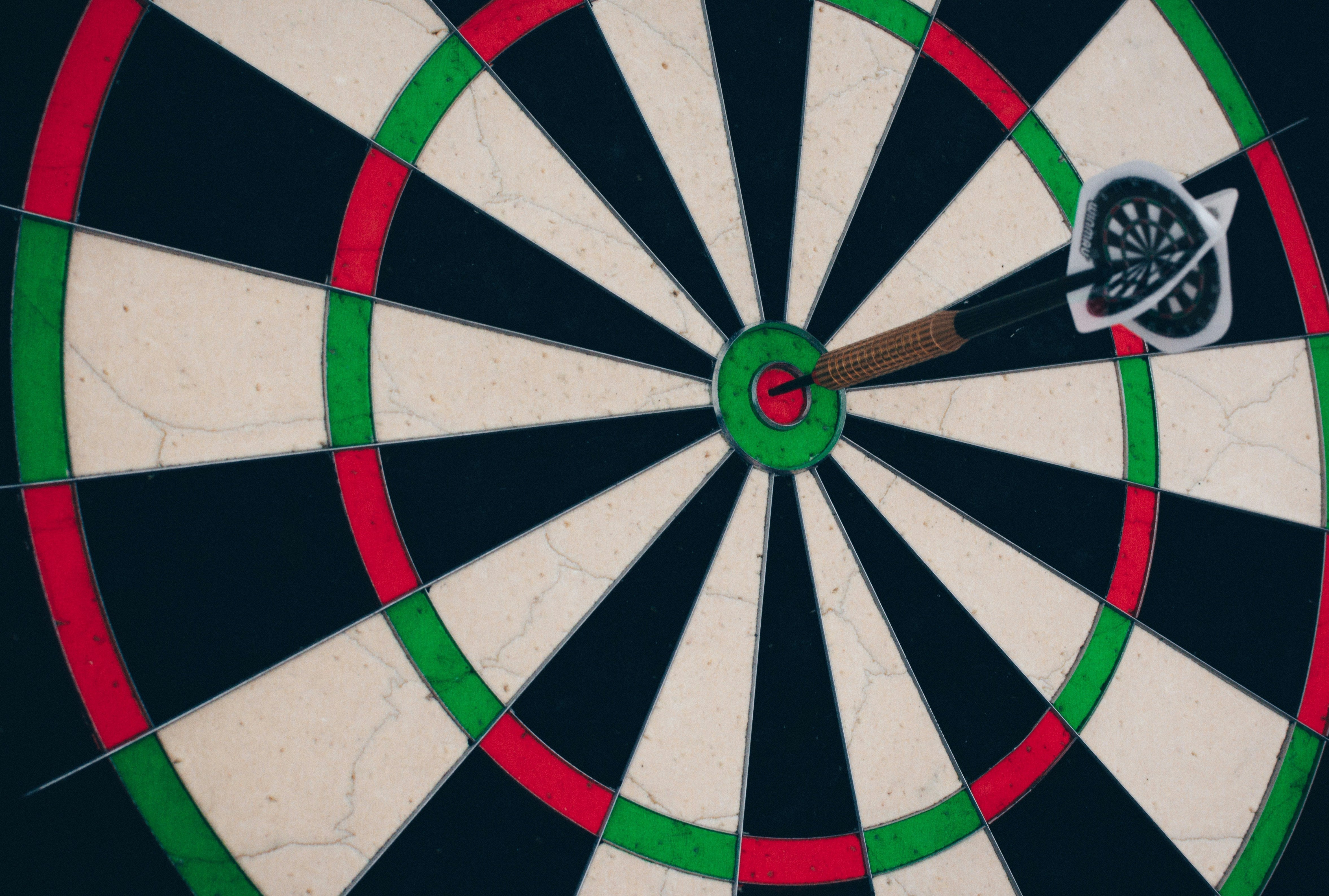Close-up of a dart embedded in the bullseye of a dartboard, illustrating targeted delivery.