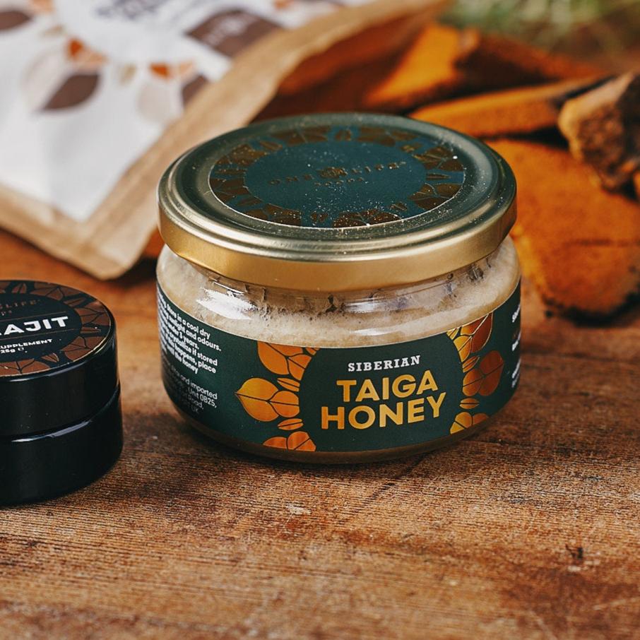 Siberian taiga honey in glass jar with gold lid on wooden surface