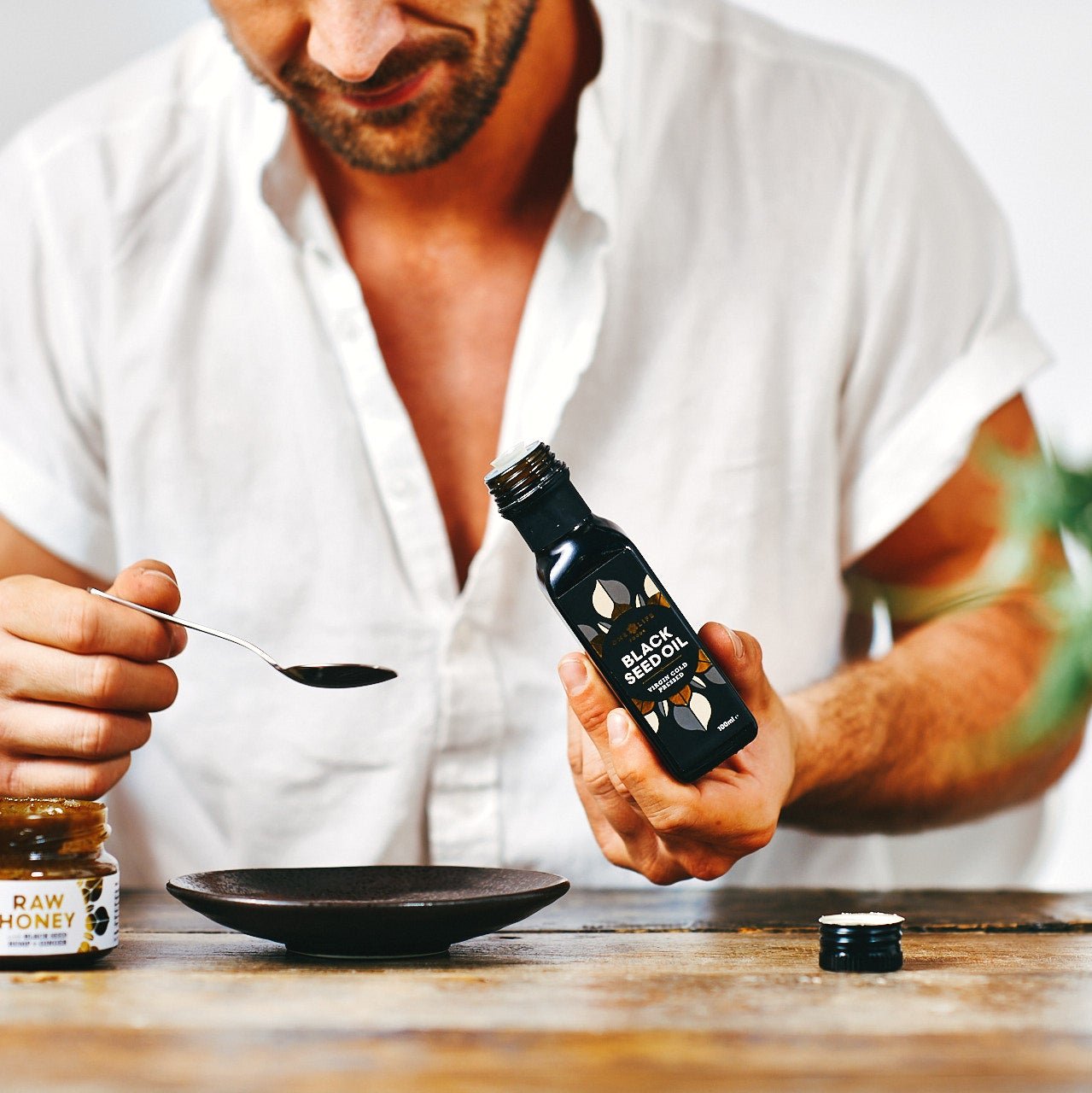 Taking black seed oil from bottle with spoon as part of daily routine