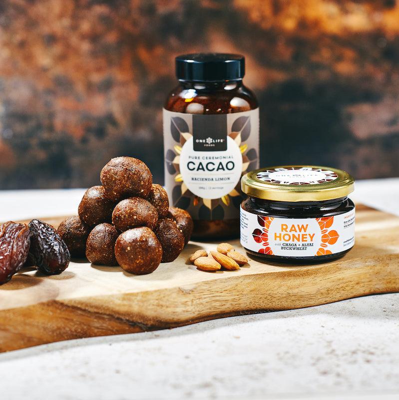 Ceremonial cacao jar with honey, dates and cacao snacks on wooden board