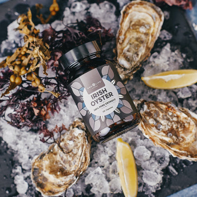 Irish Oyster Extract supplement bottle with fresh oysters on ice and lemon