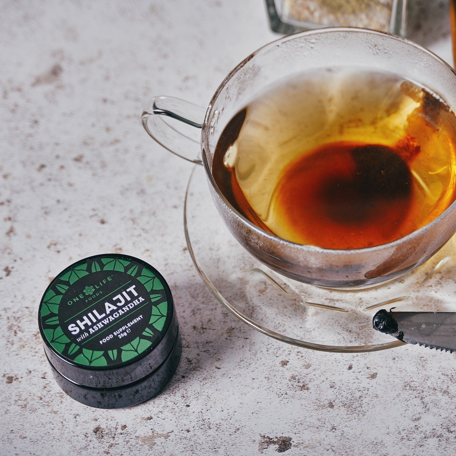 Shilajit and Ashwagandha resin UK 25g jar with a cup of green tea.