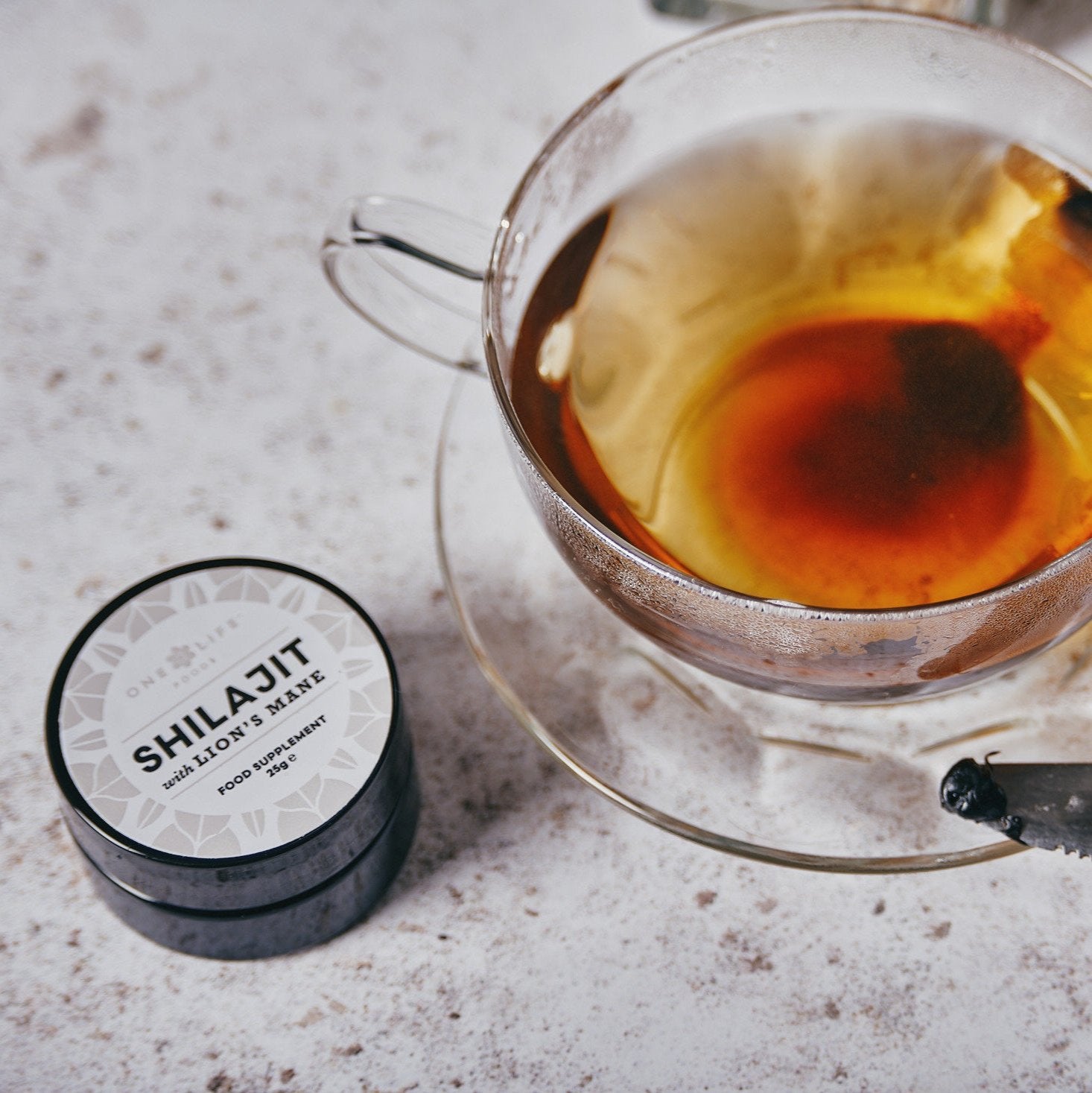 Shilajit and Lion's Mane jar with dissolved Shilajit in cup of green tea.